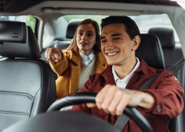 smiling-taxi-driver-with-woman-passenger-pointing-on-road-e1687241163229.jpg